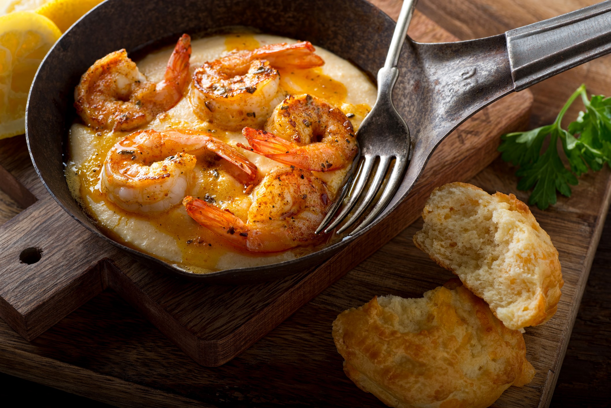 Braised prawns with shells attached in a mini serving pan. Bread at the side