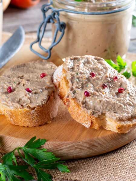 Beef and pork sandwich spread on top of sliced baguette. Served on a wooden board.