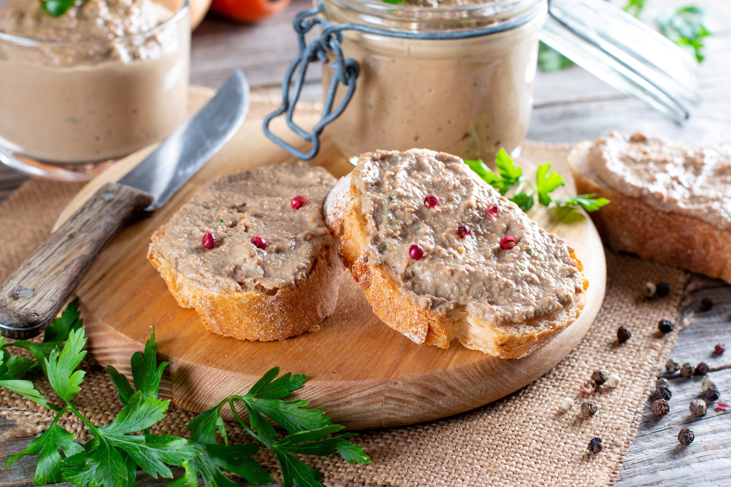 Beef and pork sandwich spread on top of sliced baguette. Served on a wooden board.