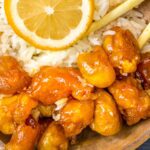 Chinese Chicken in Lemon Sauce served in a wooden bowl with chopsticks. Lemon wheel as garnish