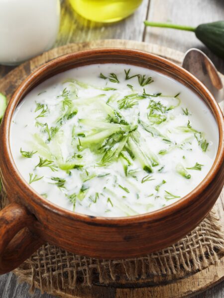 Cucumber Soup served in a brown bowl on a wooden board