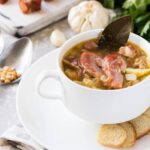 Ham Bone and Split Pea Soup served in a white bowl with small pieces of bread